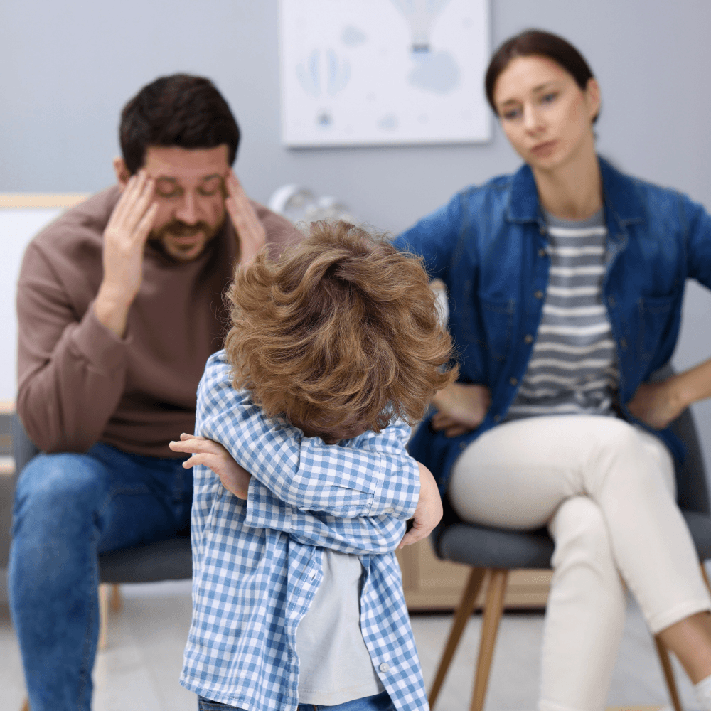 Enfant qui croise les bras avec en arrière plan ses parents en colère