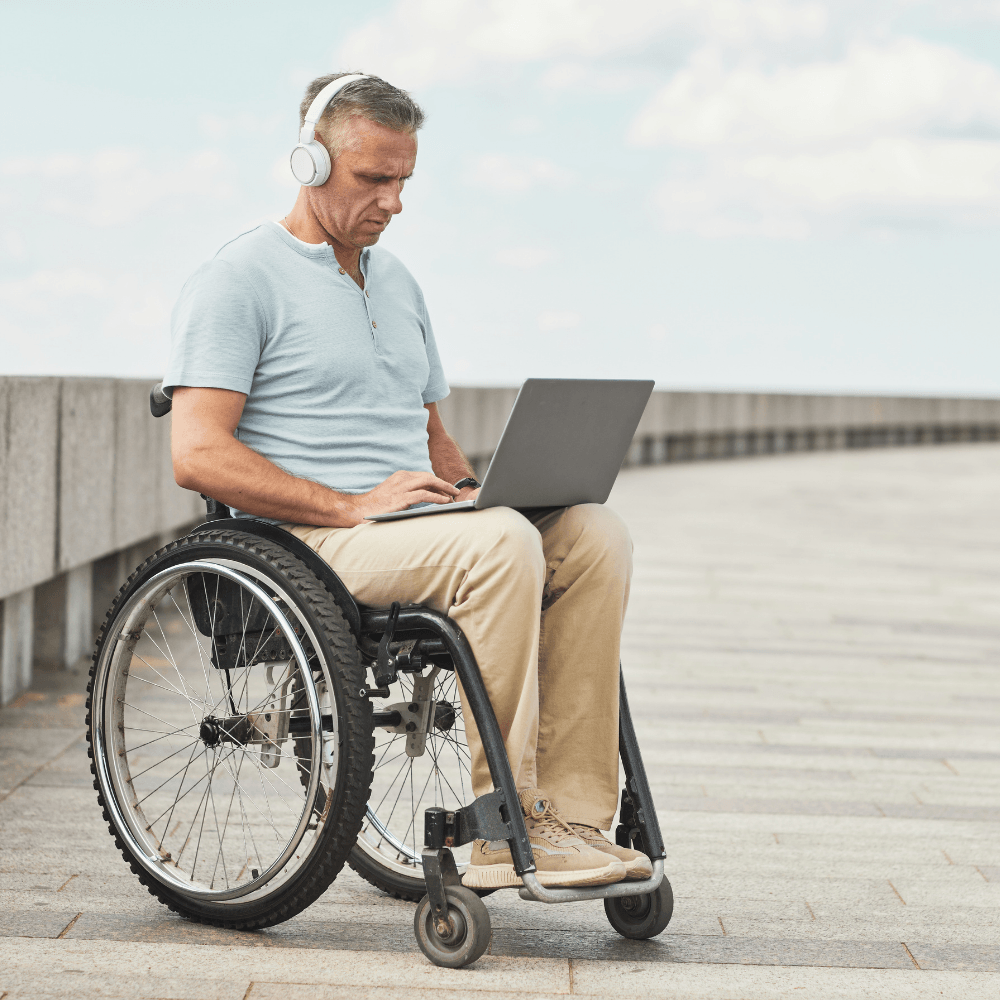Homme en fauteuil roulant avec un ordinateur portable sur les genoux